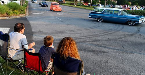 Scott McCord, left, his son John and wife Ashley watch as cars start to pour into the Mansell Crossing shopping center for the Caffeine and Octane car show on Sunday June 5, 2011. "I've been to every show," said McCord. "I love cars. They've been my downfall ever since I was a kid."