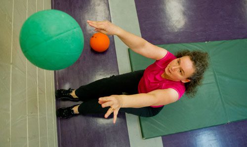 Francoise Lama-Solet throws a weight ball against the wall while doing sit ups during a personal training class at the Robert D. Fowler YMCA in Peachtree Corners on Thursday, December 13, 2012. 