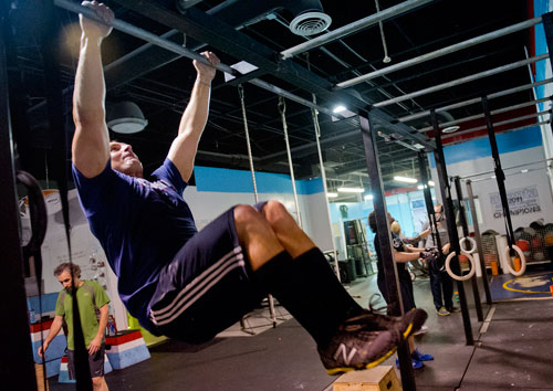 Chuck Pruitt hangs from a bar as he does pull ups during a class at CrossFit Atlanta on Thursday, December 13, 2012.