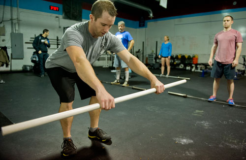 Instructor Andy Bayles (left) reviews proper form for an exercise with Jason Parrish, Leah Polaski and Chris Schmitz during a class at CrossFit Atlanta on Thursday, December 13, 2012. 