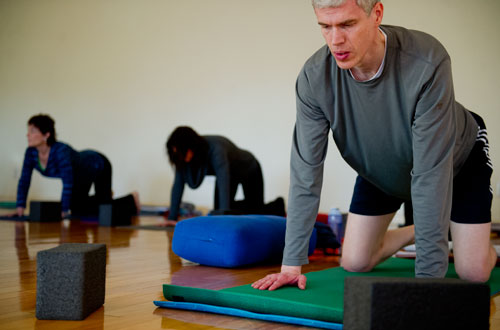 Ewan Cameron (right) warms up with a stretching exercise during a class at Plum Tree Yoga in Roswell on Friday, December 14, 2012. 