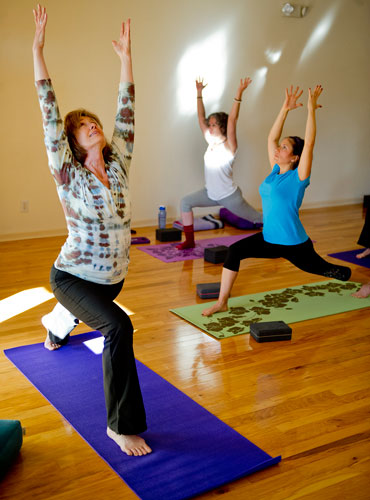 Instructor Betsy Blount (left) leads Carla Flack and Hallie Keel through a pose during a class at Plum Tree Yoga in Roswell on Friday, December 14, 2012. 