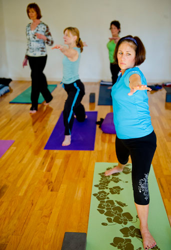 Hallie Keel (right), Patti Sopko and Jo Pascual hold a pose as instructor Betsy Blount walks through the rows of students during a class at Plum Tree Yoga in Roswell on Friday, December 14, 2012.