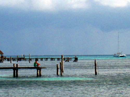 A man sits on one of the piers on Isla Mujeres as a boat passes on Thursday, January 24, 2013.