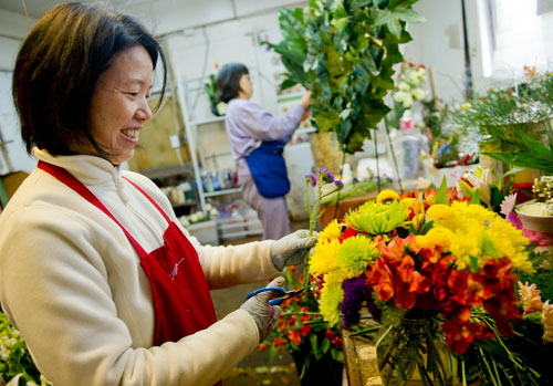 May Tsai (left) arranges flowers in a vase as Jihfang Liu arranges plants in a basket at A Blooming Earth florist shop in Decatur on Thursday, January 31, 2013.