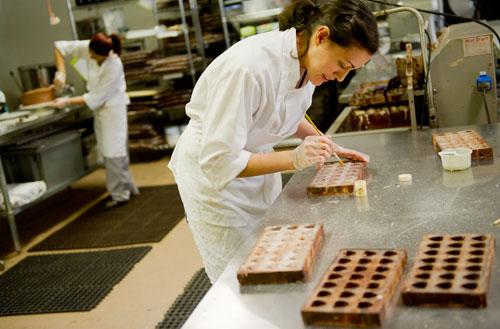 Bianca Garcia (right) prepares molds of truffles as Mabel Ramirez covers a cake in chocolate ganache at Cacao Atlanta in Inman Park on Friday, February 1, 2013.