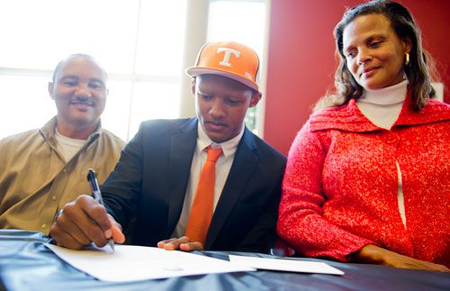 Seated between his father Robert (left) and mother Stephanie (right), Joshua Dobbs (center) signs his commitment paper to Tennessee during the National Signing Day event at Alpharetta High School in Alpharetta, Georgia on Wednesday, February 6, 2013. Dobbs started as quarterback for Alpharetta for the past two years and has officially signed to play for Tennessee.