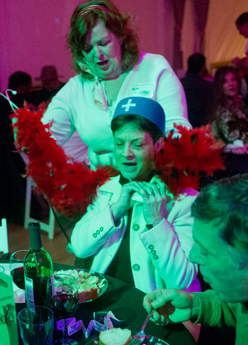Virginia Kirby (left) hands Marcy Stoll her costume as she and her husband Dave eat dinner during the murder mystery dinner Death at the Doo Wop at Blue Mark Studios in Midtown on Tuesday, February 12, 2013. 