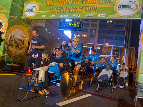Scott Rigsby (left) and Kyle Pease, pushed by his brother Brent, take off from the starting line during the 2013 Publix Georgia Marathon/Half Marathon in Atlanta on Sunday, March 17, 2013.
