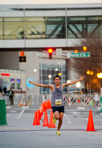 Alejandro Arreola stretches out his arms as he nears the finish line winning the 5k with a time of 17:35 during the 2013 Publix Georgia Marathon/Half Marathon in Atlanta on Sunday, March 17, 2013.