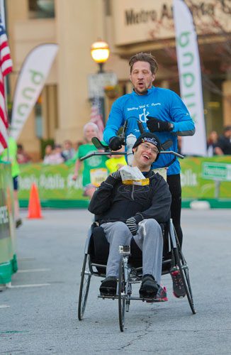 Corbin McKenzie, pushed by Stevie Dement, crosses the finish line winning the wheelchair category during the 2013 Publix Georgia Marathon/Half Marathon in Atlanta on Sunday, March 17, 2013. 