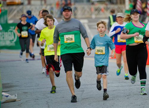Chris Woodruff (20430) holds hands with his son CJ as they near the finish line during the 2013 Publix Georgia Marathon/Half Marathon in Atlanta on Sunday, March 17, 2013.
