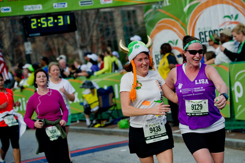 Lisa Keating (9129) and Julia Lance (9438) cross the finish line arm-in-arm during the 2013 Publix Georgia Marathon/Half Marathon in Atlanta on Sunday, March 17, 2013.