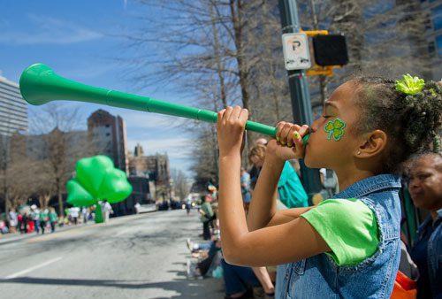 Ezabella Wilder blows into a horn as she watches the 131st Atlanta St. Patrick's Day Parade march down Peachtree Street on Saturday March 16, 2013. 