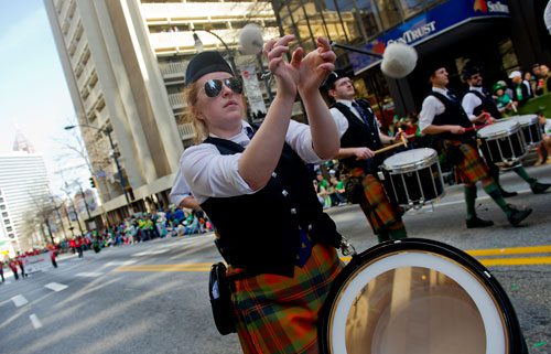 Alison Recknagel (center) twirls her drum sticks in the air as she marches down Peachtree Street with the Atlanta Pipe Band during the 131st Atlanta St. Patrick's Day Parade on Saturday March 16, 2013. 