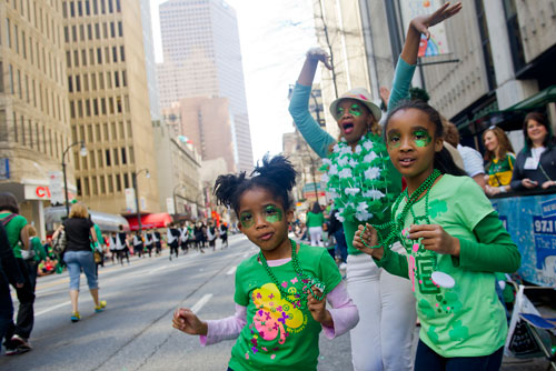 Kassidy Daniel, Marie Burrell and Lauren Daniel dance on Peachtree Street as they watch the 131st Atlanta St. Patrick's Day Parade pass by on Saturday March 16, 2013.