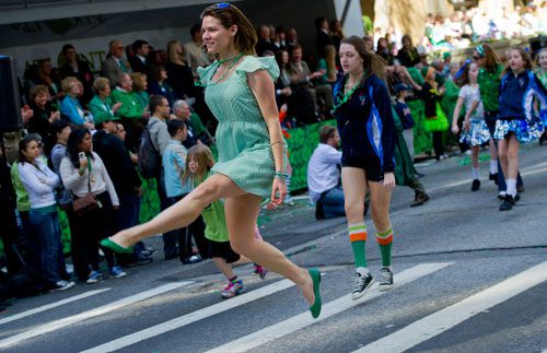 Rita Shawcross (left) leaps into the air as she dances down Peachtree Street during the 131st Atlanta St. Patrick's Day Parade on Saturday March 16, 2013.
