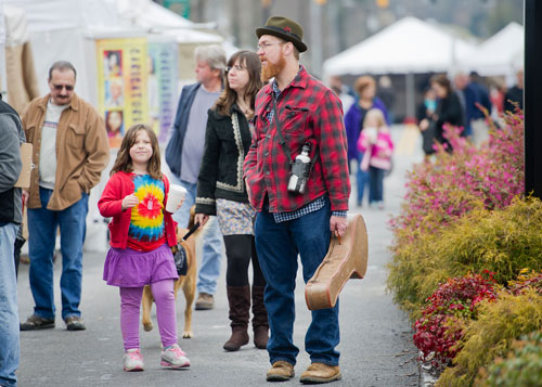 Mark Heilman (right) carries his banjo as he walks through the Stone Mountain Village Blue Grassroots Music and Arts Festival with his daughter Riona and wife Laura on Saturday, March 23, 2013.