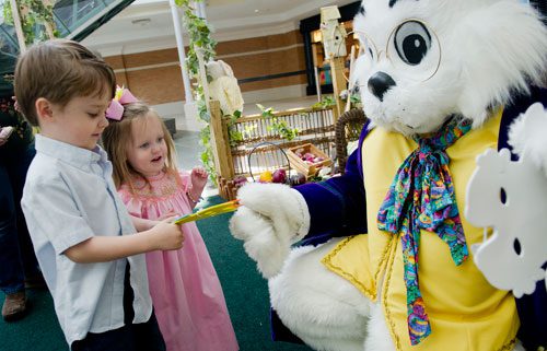 The Easter Bunny hands masks to Kylie Cornett and her brother Joshua after they visit with him at North Point Mall in Alpharetta on Thursday, March 21, 2013. 