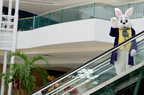 The Easter Bunny waves as he rides the escalator at North Point Mall in Alpharetta on Thursday, March 21, 2013.