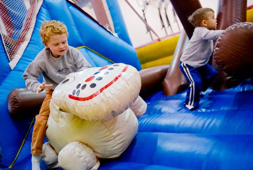 Luke DeLay (left) and Brock Lowe bounce around on an inflatable playground during the fifth annual Easter Egg Hunt at Hebron Christian Church in Winder on Sunday, March 24, 2013.