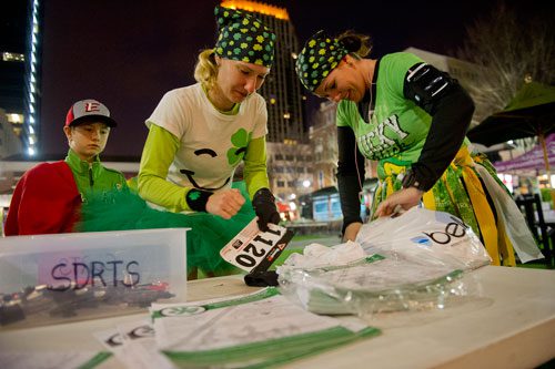 Lisa Askue (right) and Michelle Stenzel attach their bib numbers to their shirts as Stenzel's son Andrew watches before the start of the Junior League of Atlanta's 9th annual ShamRock 'N Roll Road Race on Sunday, March 10, 2013. 