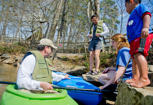 Oscar Hernandez (right) watches as Randy Renbarger (left) and his daughter Rachel (center) hold a kayak steady for his wife Jill while she puts on her life jacket before they paddle on the Chattahoochee River at Jones Bridge Park in Peachtree Corners on Saturday, March 30, 2013. 