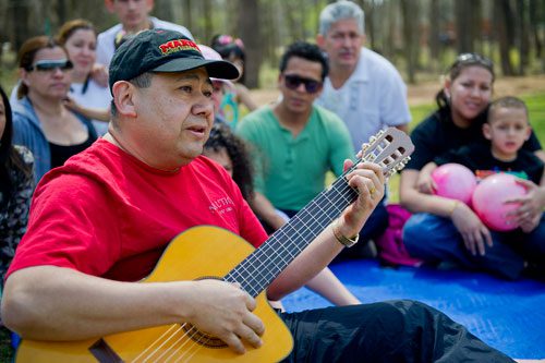 Jesus Melendez plays the guitar for a group of parishioners from New Jerusalem Church after a river baptism ceremony at Jones Bridge Park in Peachtree Corners on Saturday, March 30, 2013. 