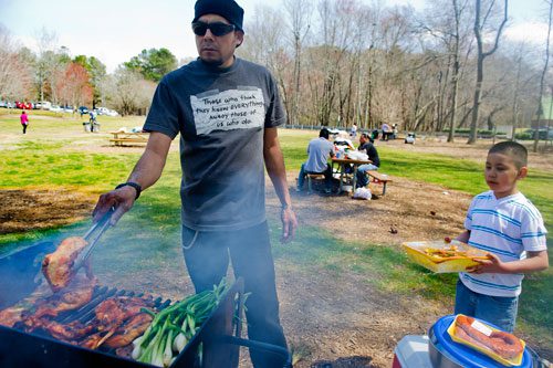Octavio Escobedo (left) turns chicken on the grill as Brandon Perez holds a tray of meat at Jones Bridge Park in Peachtree Corners on Saturday, March 30, 2013. 