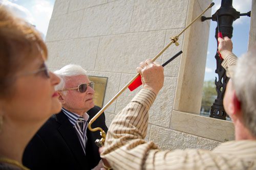 Abe Besser (center) and his wife Marlene have help lighting the first torch at the Besser Holocaust Memorial Garden from one of Besser's cousins Harry Sheinfield during the Yom HaShoah Commemoration ceremony at the Marcus Jewish Community Center of Atlanta in Dunwoody on Sunday, April 7, 2013.