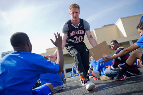 Jakob Gollon, a junior forward from Mercer University, hands out high fives as he works as a coach during the Allstate NABC Good Works Team Basketball Clinic at Atlantic Station in Atlanta on Sunday, April 7, 2013. 