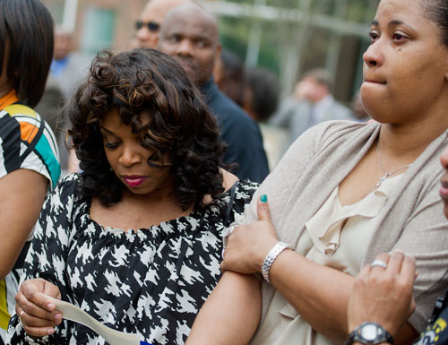 Kimberly Freeman (left) looks down at the name of Gail Thomas, her god daughter, as she stands next to Trinia Favors, Thomas' aunt, during the unveiling of three officers' names on the Georgia Law Enforcement Memorial Wall outside of the Public Safety Headquarters in Atlanta on Thursday, April 11, 2013. 