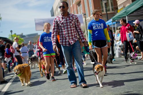 Jamie Voisin (center) walks with his dog Doegie along the route for the Atlanta Humane Society's 23rd annual Pet Parade at Atlantic Station in Atlanta on Saturday, April 13, 2013. 