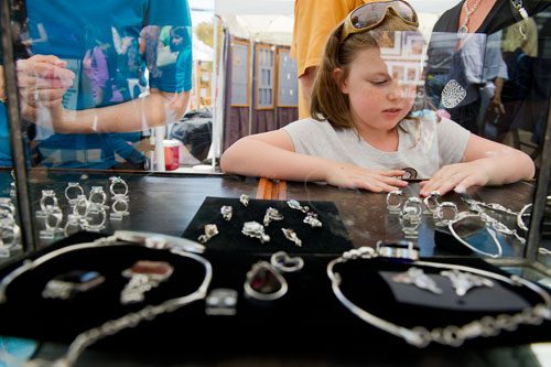 Nicole Jordan looks at the jewelry for sale in Joanie Muhfelder's booth during the Alpharetta Arts Streetfest on Saturday, April 13, 2013.