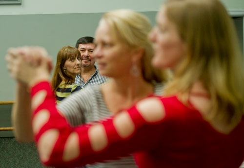 Michele Rabanal (left) holds onto her husband Victor as they watch Joan Sanborn learn a move with All About Ballroom instructor Kathy Casper during a salsa class in Alpharetta on Saturday, April 13, 2013.