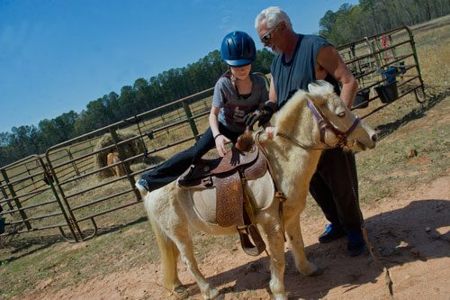 Dennis Horion (right) helps Sydney Gray mount her pony for their eight mile trail ride with the Adopt-A-Horse organization in Covington on Tuesday, April 2, 2013.