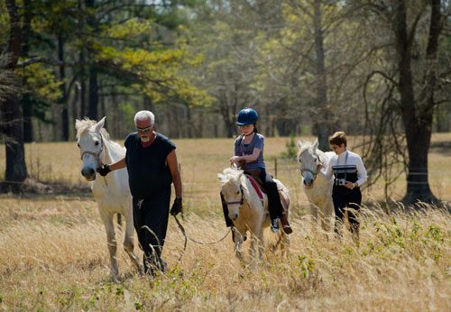 Dennis Horion (left), Sydney Gray and Linda Gray lead their horses and pony through a field before leaving on an eight mile trail ride in Covington on Tuesday, April 2, 2013.