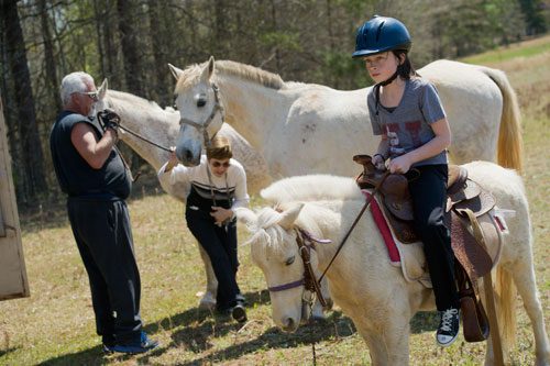 Sydney Gray (right) sits atop her pony as Dennis Horion (left) and Linda Gray wrangle some horses for a trail ride in Covington on Tuesday, April 2, 2013.
