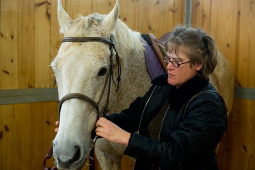 Dana McDaniel fits a bridal on one of the horses she uses for lessons at Little Creek Horse Farm in Decatur on Wednesday, April 3, 2013.
