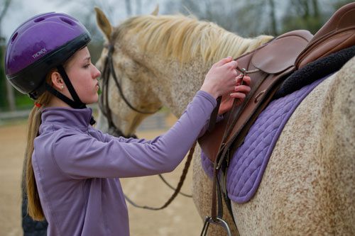 Julia Fleischer makes sure the straps on her saddle are tight before taking a riding lesson at Little Creek Horse Farm in Decatur on Wednesday, April 3, 2013.