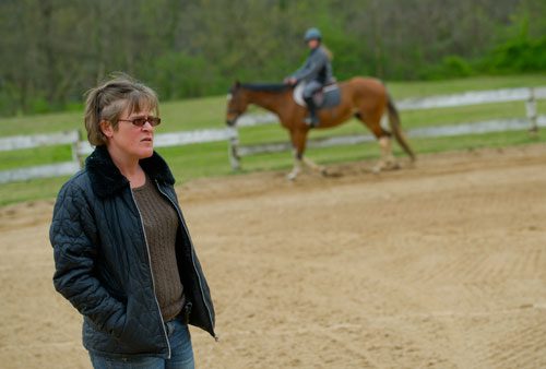 Dana McDaniel (left) watches her students ride their horses around the training ring at Little Creek Horse Farm in Decatur on Wednesday, April 3, 2013.