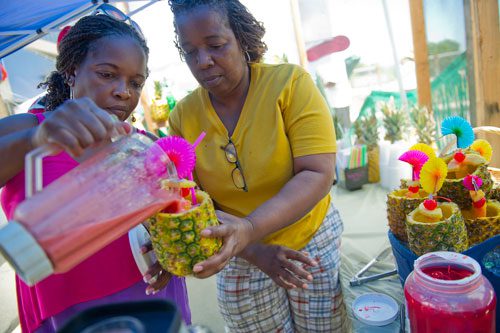 Sisters Elaine Lane (left) and Patricia Henry make drink filled pineapples during the 25th annual Atlanta Caribbean Carnival at Morris Brown Herndon Stadium in Atlanta on Saturday, May 25, 2013.