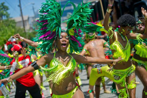 Kimberly Sandy (center) dances her way up Martin Luther King Dr. during the parade for the 25th annual Atlanta Caribbean Carnival at Morris Brown Herndon Stadium in Atlanta on Saturday, May 25, 2013.