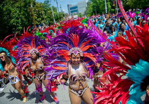 Natasha Etienne (center) dances her way up Martin Luther King Dr. during the parade for the 25th annual Atlanta Caribbean Carnival at Morris Brown Herndon Stadium in Atlanta on Saturday, May 25, 2013. 