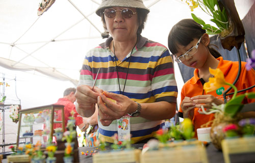 Kowit Jitpraphai (left) and his daughter Supakan design clay orchids during the Decatur Arts festival in downtown Decatur on Saturday, May 25, 2013. 