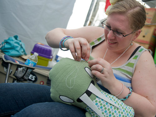 Kelly Shull sews the ear onto one of the stuffed animals designed by her husband Spencer in the jellykoe booth during the Decatur Arts festival in downtown Decatur on Saturday, May 25, 2013.