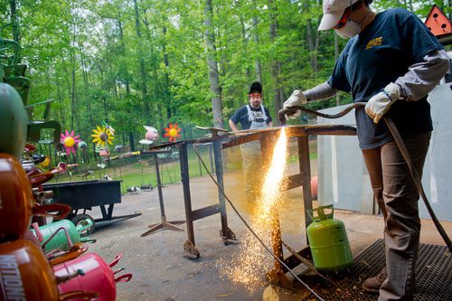 Marlene Hopkins (right) uses a plasma torch to cut one of the steel sculptures she and her husband Jimmy create at their home in Woodstock on Monday, April 29, 2013.
