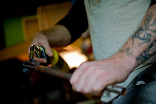 Alex Wright uses a torch to heat a brand before marking the Urban Attic symbol on a mixed media piece that he and his partner Jennie Juechter created at their home in East Point on Tuesday, April 30, 2013.