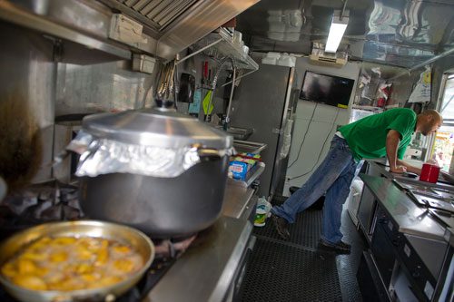Troy Anglin takes a lunch order from inside the One Love Jerk Grill truck at the Atlanta Food Truck Park & Market off of Howell Mill Road on Saturday, May 11, 2013. 