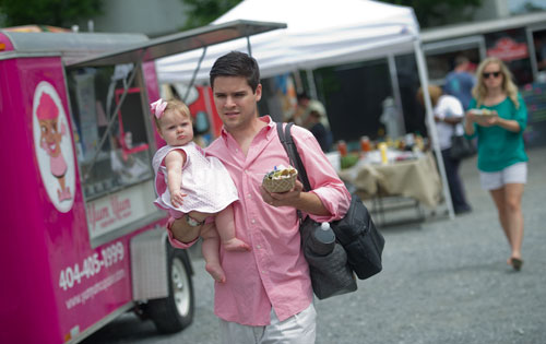 Philip Sprouse carries his daughter Ellie along with lunch as they find an empty seat to eat at the Atlanta Food Truck Park & Market off of Howell Mill Rd. on Saturday, May 11, 2013.